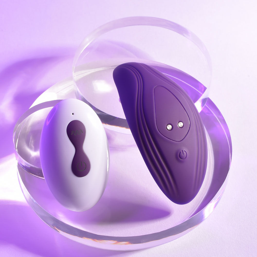 Top view of the purple Playboy Pleasure 'Our Little Secret' vibrating panties with remote control, on a purple background | Flirty Bay adult store and lingerie store